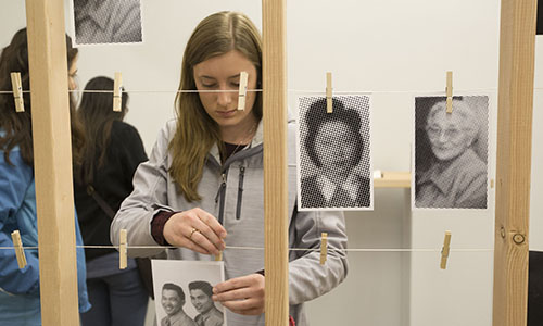 Student hanging up photos.