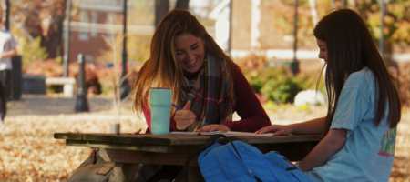 Two girls studying at a picnic table.