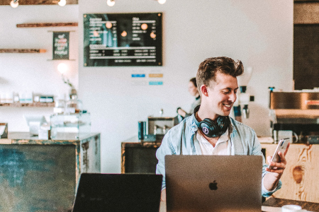 A man working on a laptop in a coffee shop.