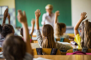 Children raising their hand in a classroom.