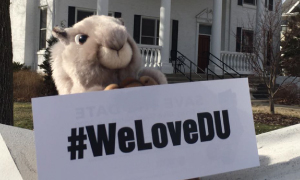 A stuffed animal squirrel holding a #WeLoveDU sign.