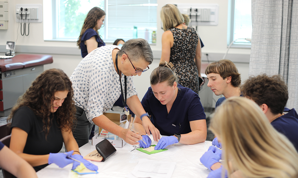 An instructor working with Physician Assistant students on a project at a table