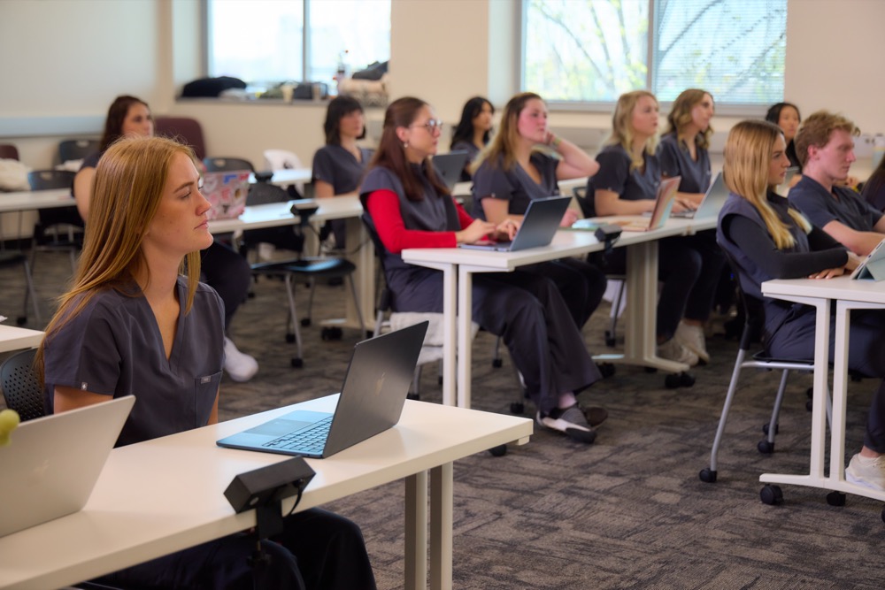 a group of Drury PA students sitting in a well-lit classroom, all facing the same direction as they learn.
