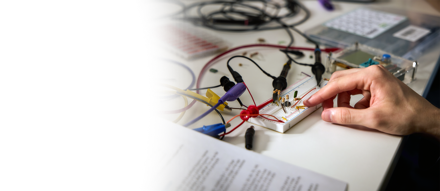 a drury student setting up an electronic circuit board. the photo shows their hand and some paperwork.