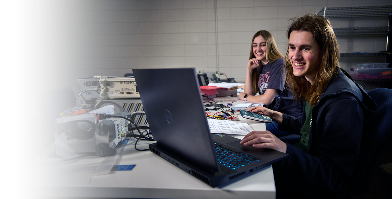 Two drury engineering students working on the computer smiling.