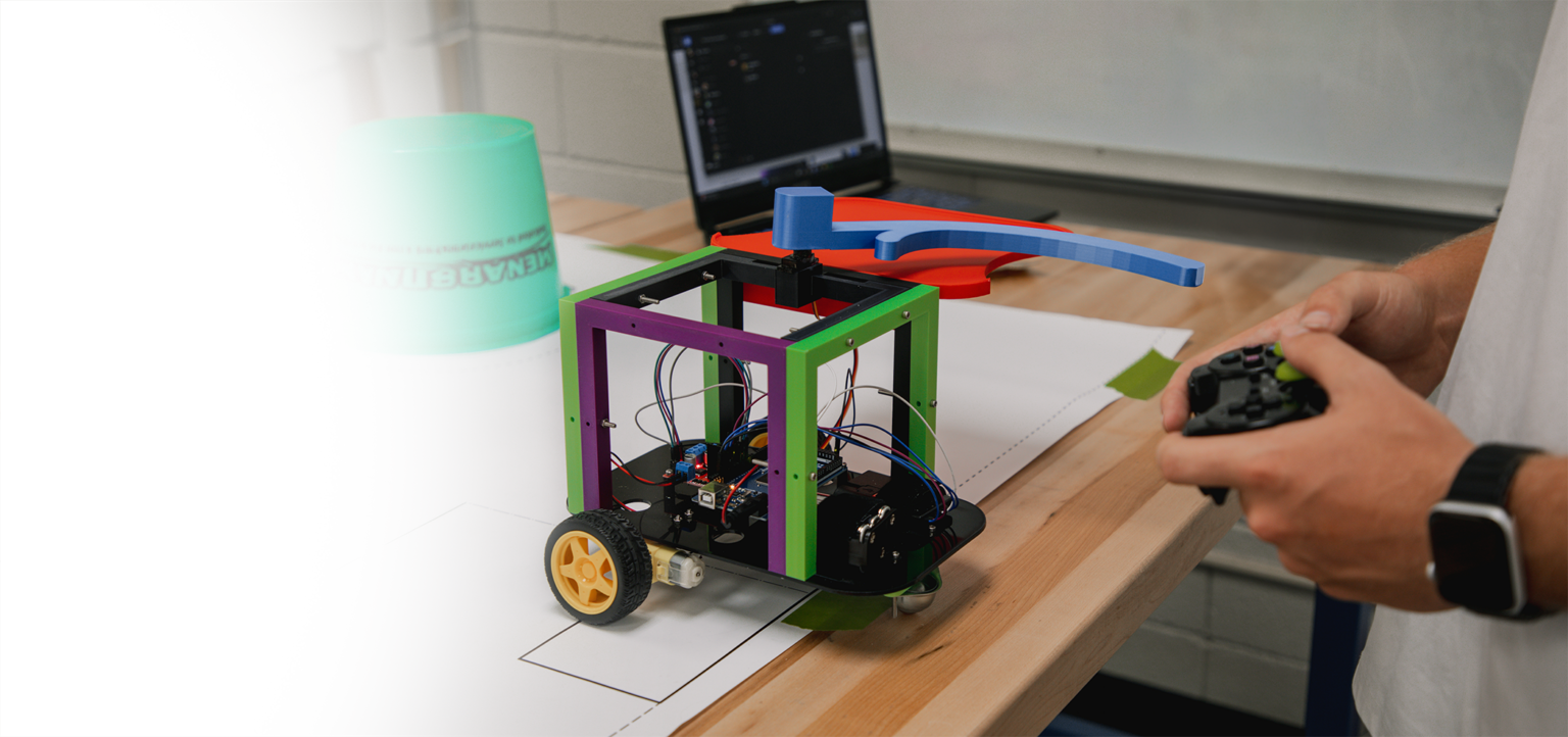 a photo displaying the hands of an Drury Engineering student holding a game controller to control a robot they built and programmed.
